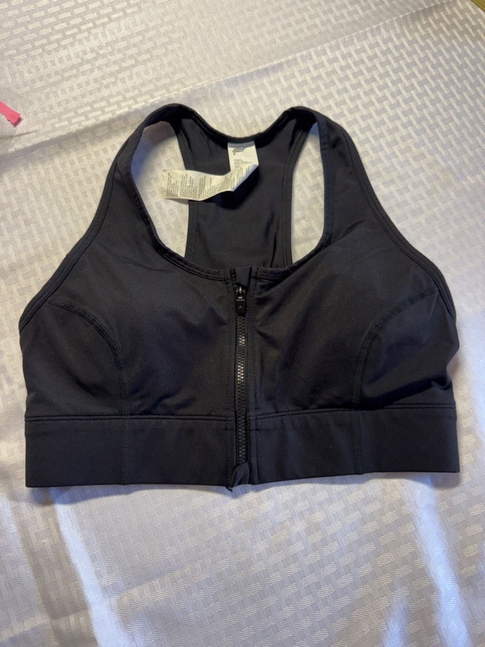 Fabletics On-The-Go Zip Medium Impact Sports Bra in black.